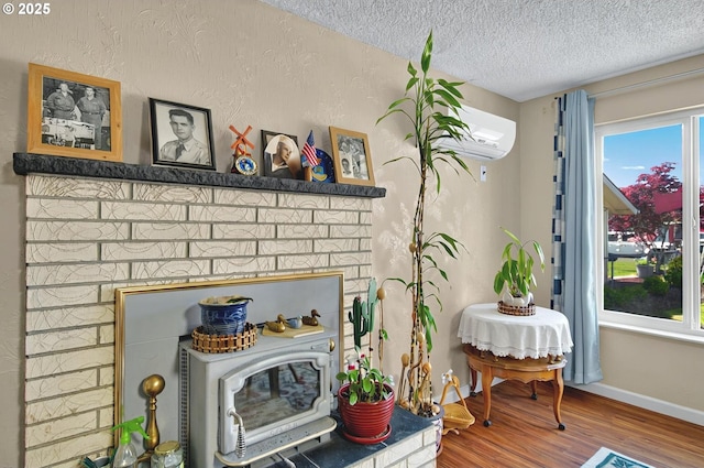 sitting room with baseboards, a textured ceiling, a wall mounted AC, and wood finished floors