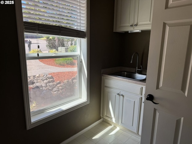interior space featuring a sink, light tile patterned floors, and baseboards