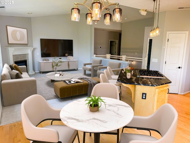 interior space with an inviting chandelier, light wood finished floors, a tile fireplace, and visible vents