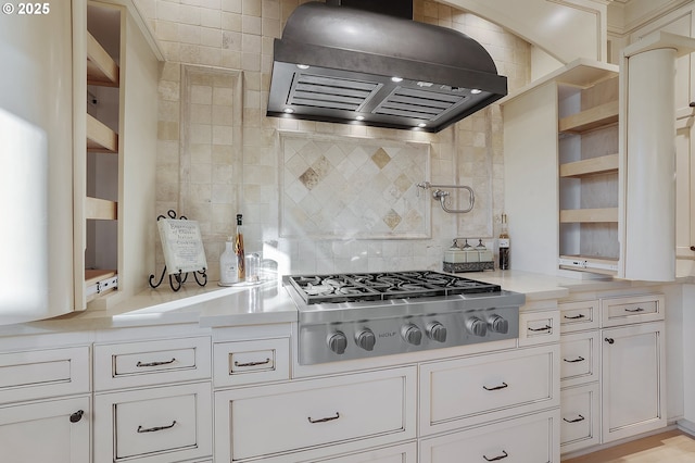 kitchen with white cabinetry, stainless steel gas stovetop, custom range hood, and backsplash