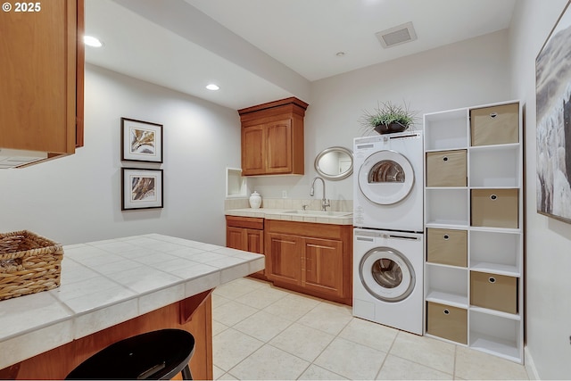 clothes washing area featuring cabinets, stacked washing maching and dryer, sink, and light tile patterned floors