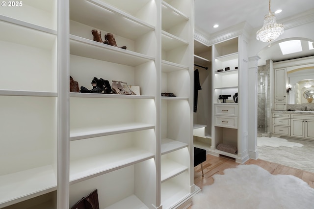 spacious closet with sink, light hardwood / wood-style flooring, and ornate columns