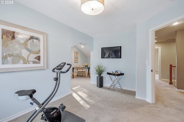 exercise room with vaulted ceiling and light carpet