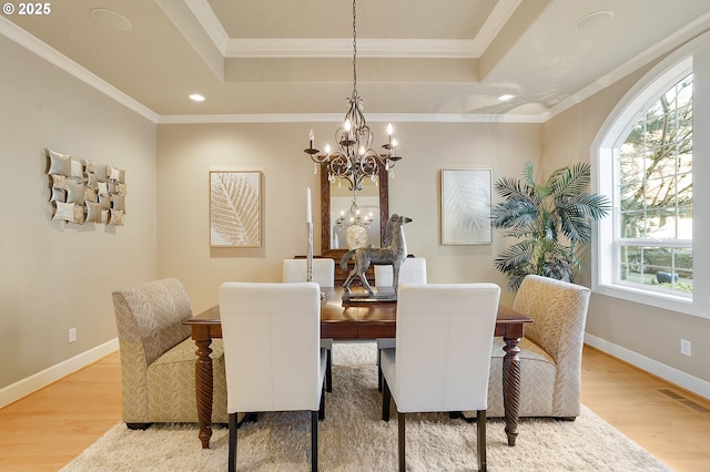 dining space with a raised ceiling, ornamental molding, a healthy amount of sunlight, and hardwood / wood-style floors