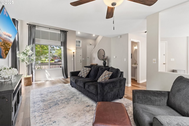 living room featuring light wood-type flooring, ceiling fan, and baseboards