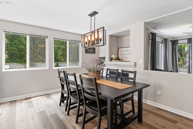 dining space with baseboards, wood finished floors, and a chandelier