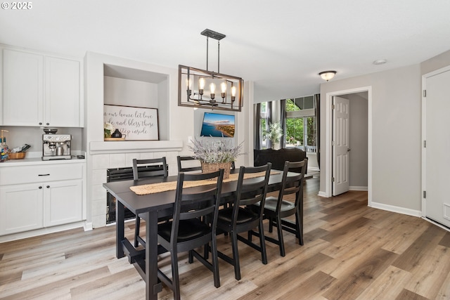 dining room with light wood finished floors, a chandelier, and baseboards