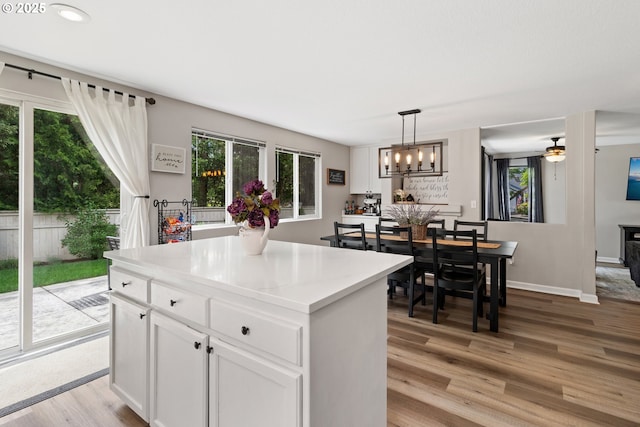 kitchen featuring light wood finished floors, white cabinetry, hanging light fixtures, a center island, and light countertops