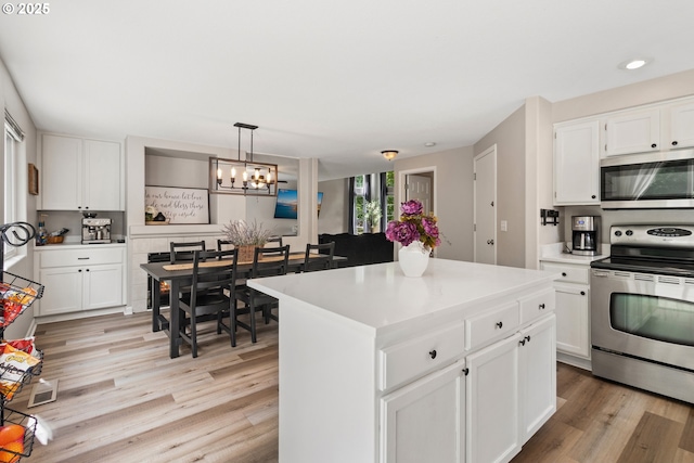 kitchen featuring appliances with stainless steel finishes, a chandelier, light wood-style floors, and white cabinetry