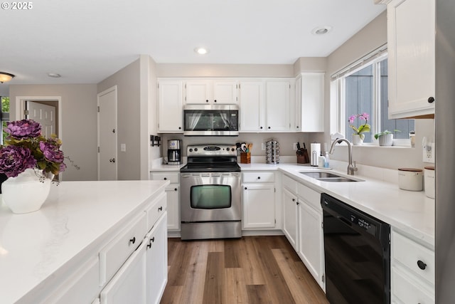 kitchen featuring stainless steel appliances, a sink, white cabinetry, wood finished floors, and light countertops