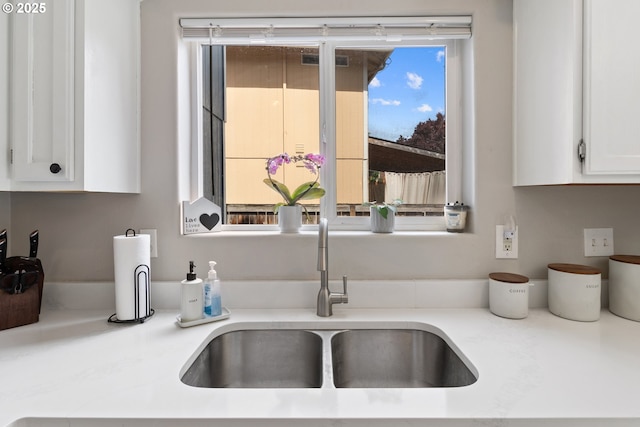 kitchen featuring a sink, white cabinets, plenty of natural light, and light countertops