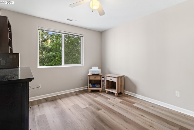 office featuring light wood-style flooring, a ceiling fan, and baseboards