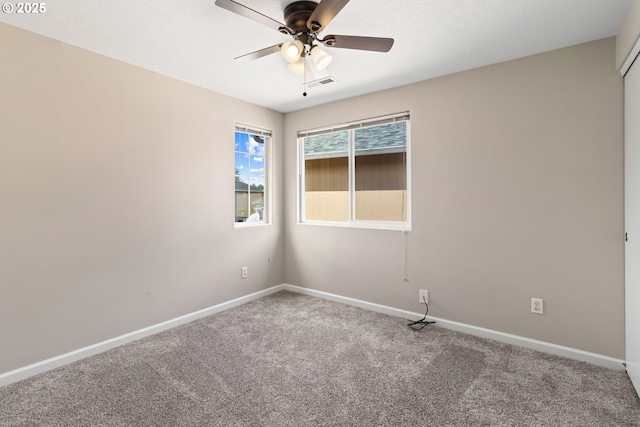 carpeted empty room featuring ceiling fan and baseboards