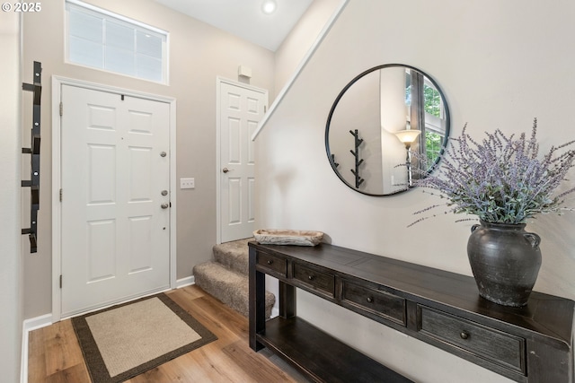 foyer featuring wood finished floors, stairway, baseboards, and recessed lighting