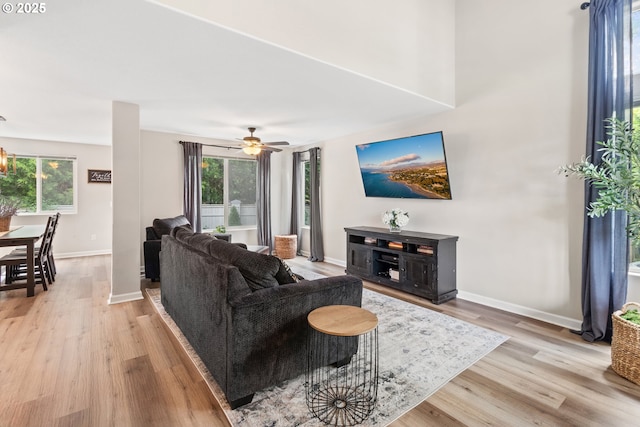 living room with light wood-style flooring, baseboards, and ceiling fan