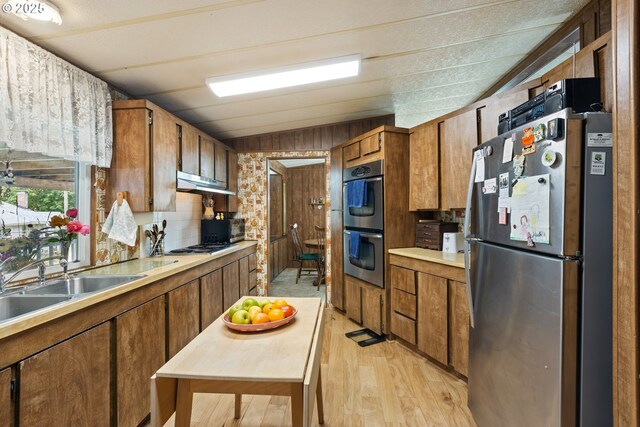 1548 Harlan St, Roseburg, OR 97471 - kitchen with appliances with stainless steel finishes, light wood-style floors, brown cabinetry, light countertops, and under cabinet range hood