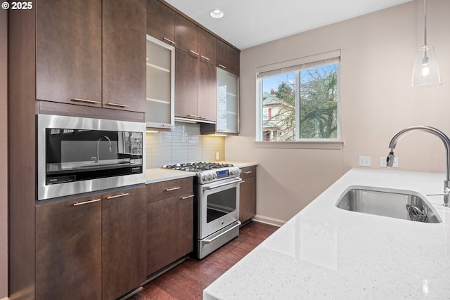 kitchen with a sink, stainless steel appliances, backsplash, and dark brown cabinetry