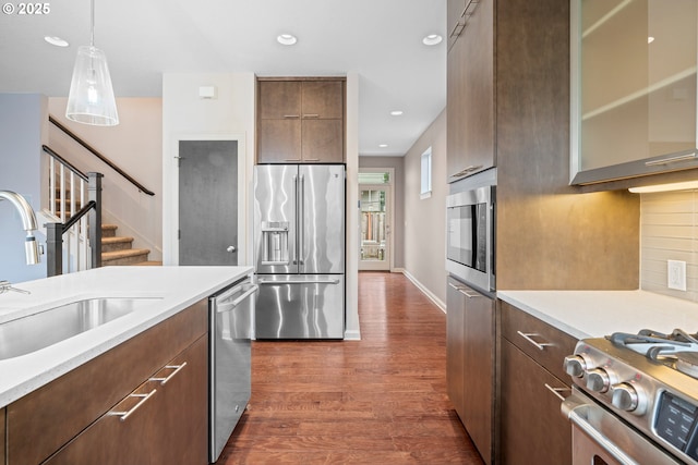 kitchen with dark wood-type flooring, a sink, stainless steel appliances, light countertops, and decorative backsplash