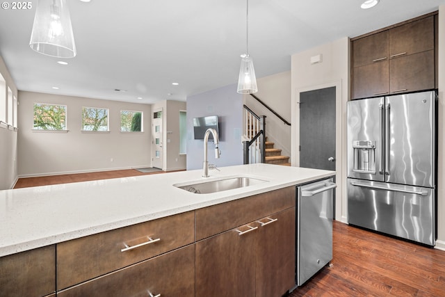 kitchen featuring dark wood-style floors, a sink, stainless steel appliances, dark brown cabinetry, and decorative light fixtures