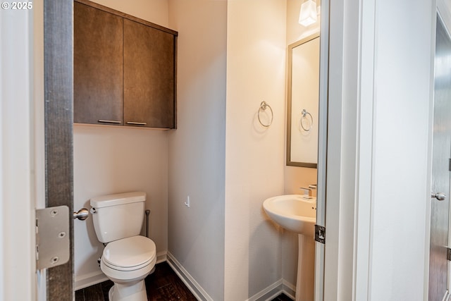 half bath featuring toilet, baseboards, and wood finished floors