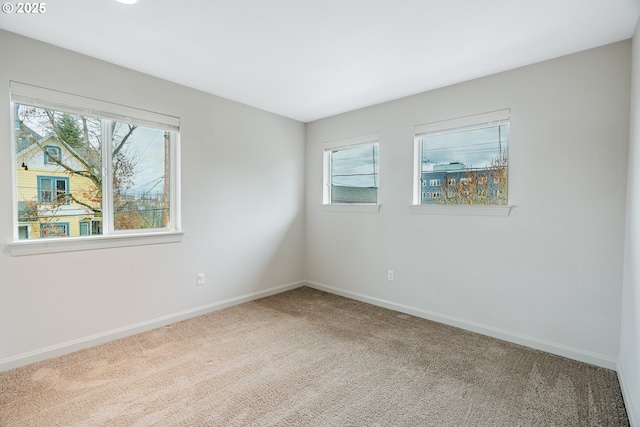 empty room with a wealth of natural light, baseboards, and carpet flooring