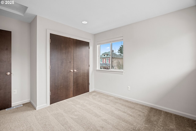 unfurnished bedroom with a closet, carpet floors, baseboards, and visible vents