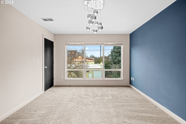 unfurnished room featuring a notable chandelier, carpet flooring, visible vents, and baseboards