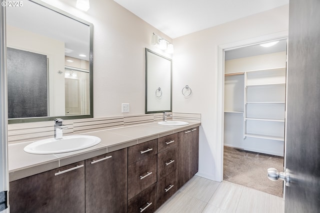 bathroom featuring a sink, a spacious closet, double vanity, and tile patterned floors