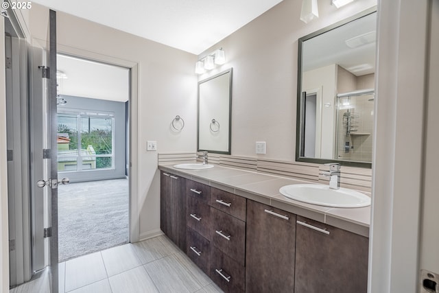 bathroom with double vanity, an enclosed shower, tile patterned floors, and a sink