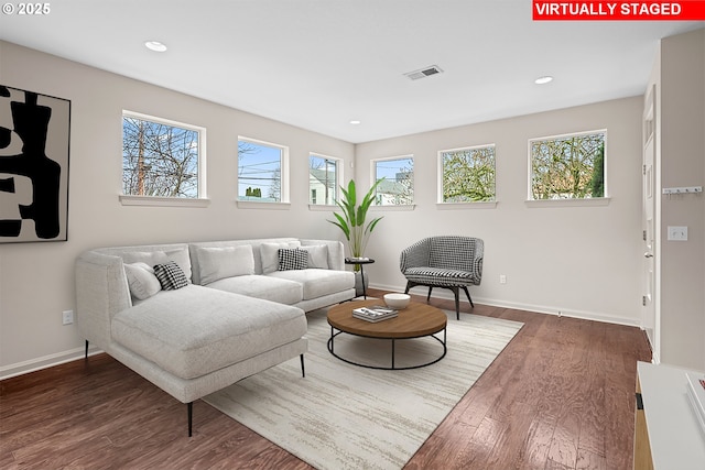 living room with a wealth of natural light, visible vents, and wood finished floors