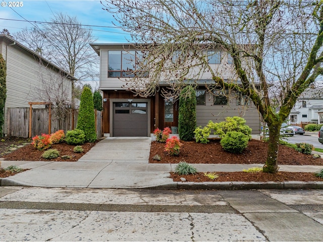 view of front of house featuring a garage, concrete driveway, and fence