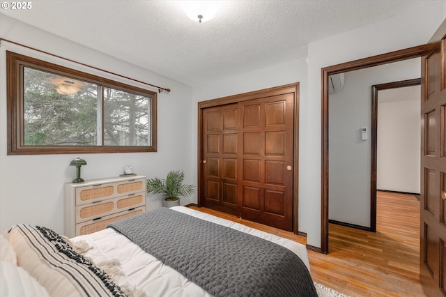 bedroom featuring light wood-type flooring, a closet, and a textured ceiling