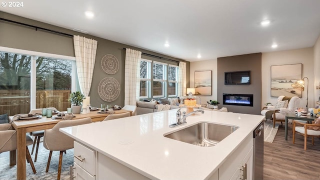 kitchen with a sink, light countertops, white cabinets, and open floor plan