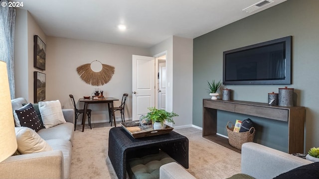 living room featuring baseboards, visible vents, and light carpet