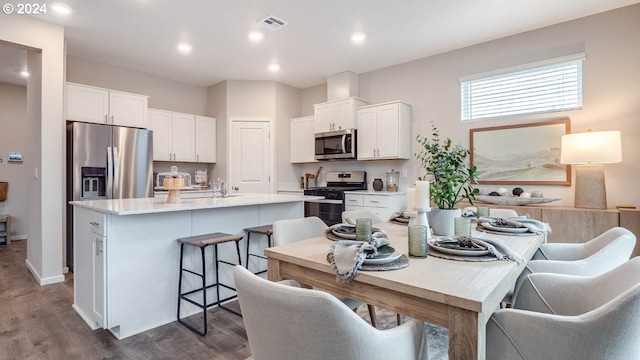 kitchen featuring visible vents, light countertops, a kitchen island with sink, appliances with stainless steel finishes, and white cabinets