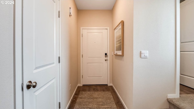 doorway to outside featuring baseboards and dark wood finished floors