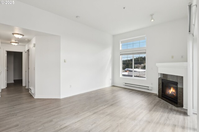 unfurnished living room with baseboards, a baseboard heating unit, wood finished floors, and a tile fireplace