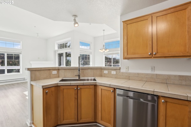 kitchen with a peninsula, stainless steel dishwasher, plenty of natural light, and a sink