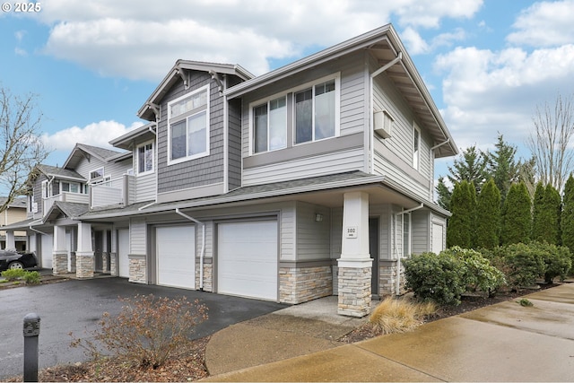 view of front of home featuring aphalt driveway, stone siding, and an attached garage