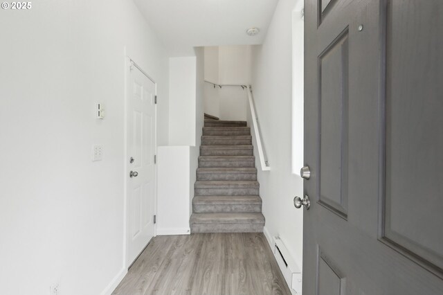 entryway featuring a baseboard heating unit, stairway, light wood-style flooring, and baseboards