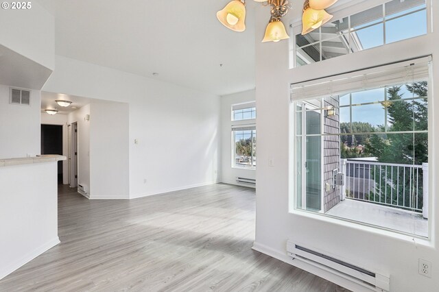 spare room featuring baseboards, a baseboard radiator, visible vents, and wood finished floors