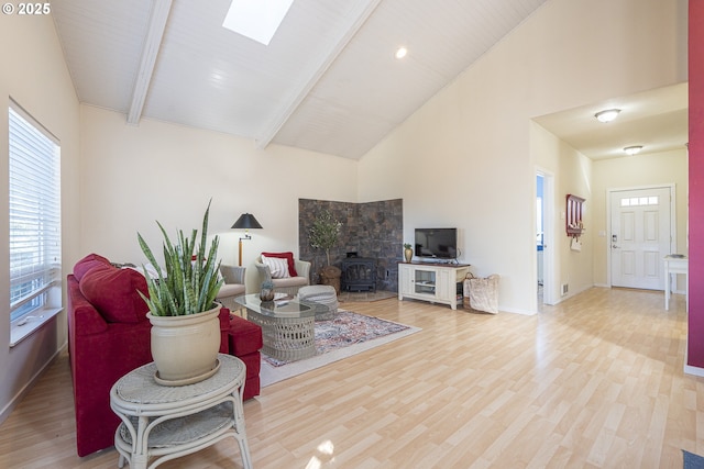 living area with wood finished floors, high vaulted ceiling, beam ceiling, baseboards, and a skylight