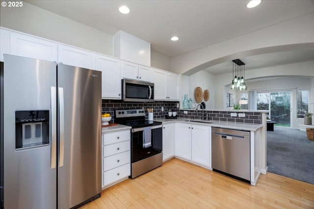 kitchen with tasteful backsplash, appliances with stainless steel finishes, a peninsula, and a sink