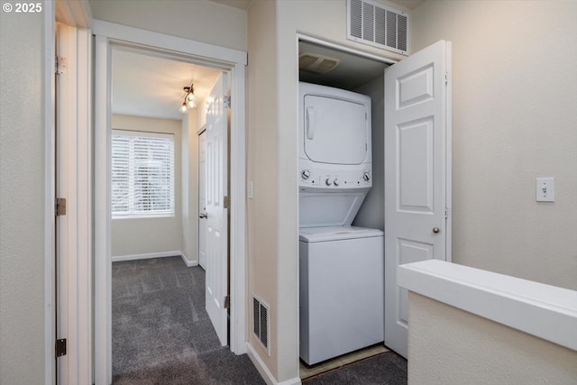 washroom featuring laundry area, dark carpet, stacked washing maching and dryer, and visible vents