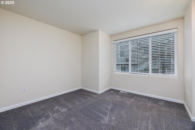 unfurnished room featuring baseboards and dark colored carpet