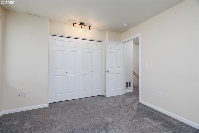 unfurnished bedroom featuring carpet, visible vents, a closet, and baseboards