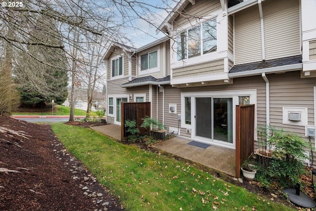 rear view of house featuring a patio area, a shingled roof, and a yard