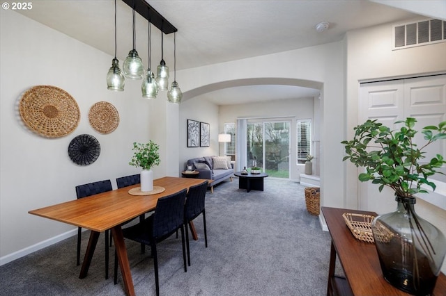 dining room with arched walkways, visible vents, baseboards, and carpet