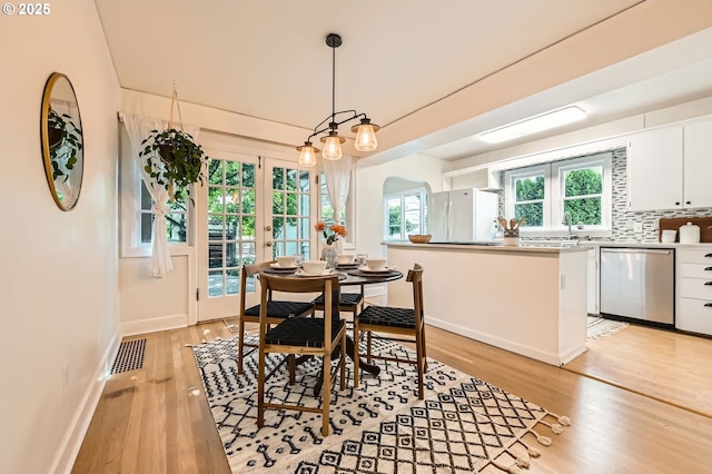 3954 NE 38th Ave, Portland, OR 97212 - dining room featuring light wood-style floors, arched walkways, french doors, and plenty of natural light