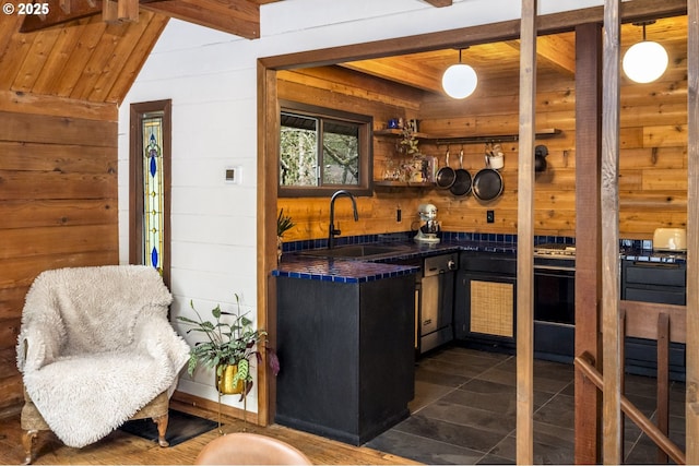 kitchen featuring a sink, dark countertops, wood ceiling, and wooden walls